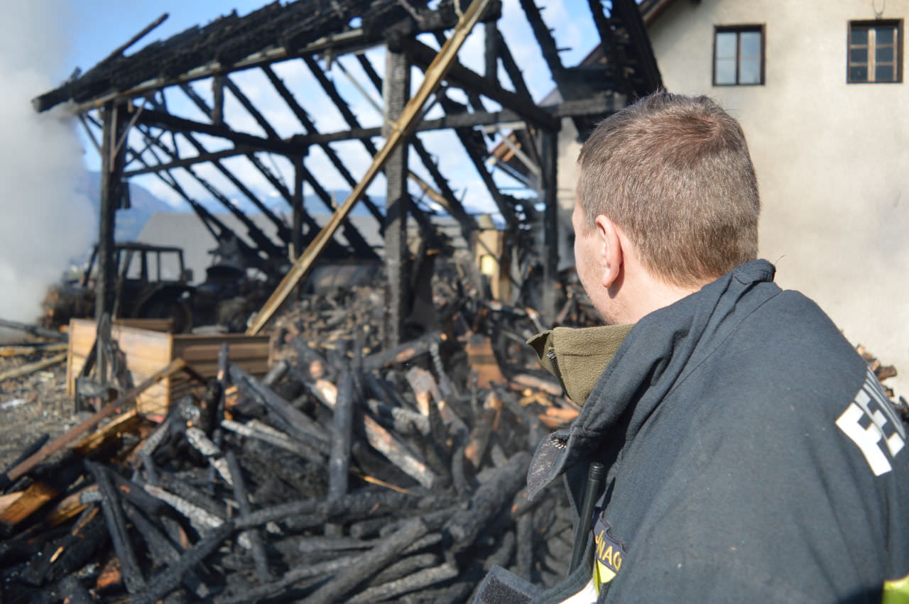 Ein Freiwilliger Feuerwehrmann vor dem zerstörten Wirtschaftsgebäude in Saak