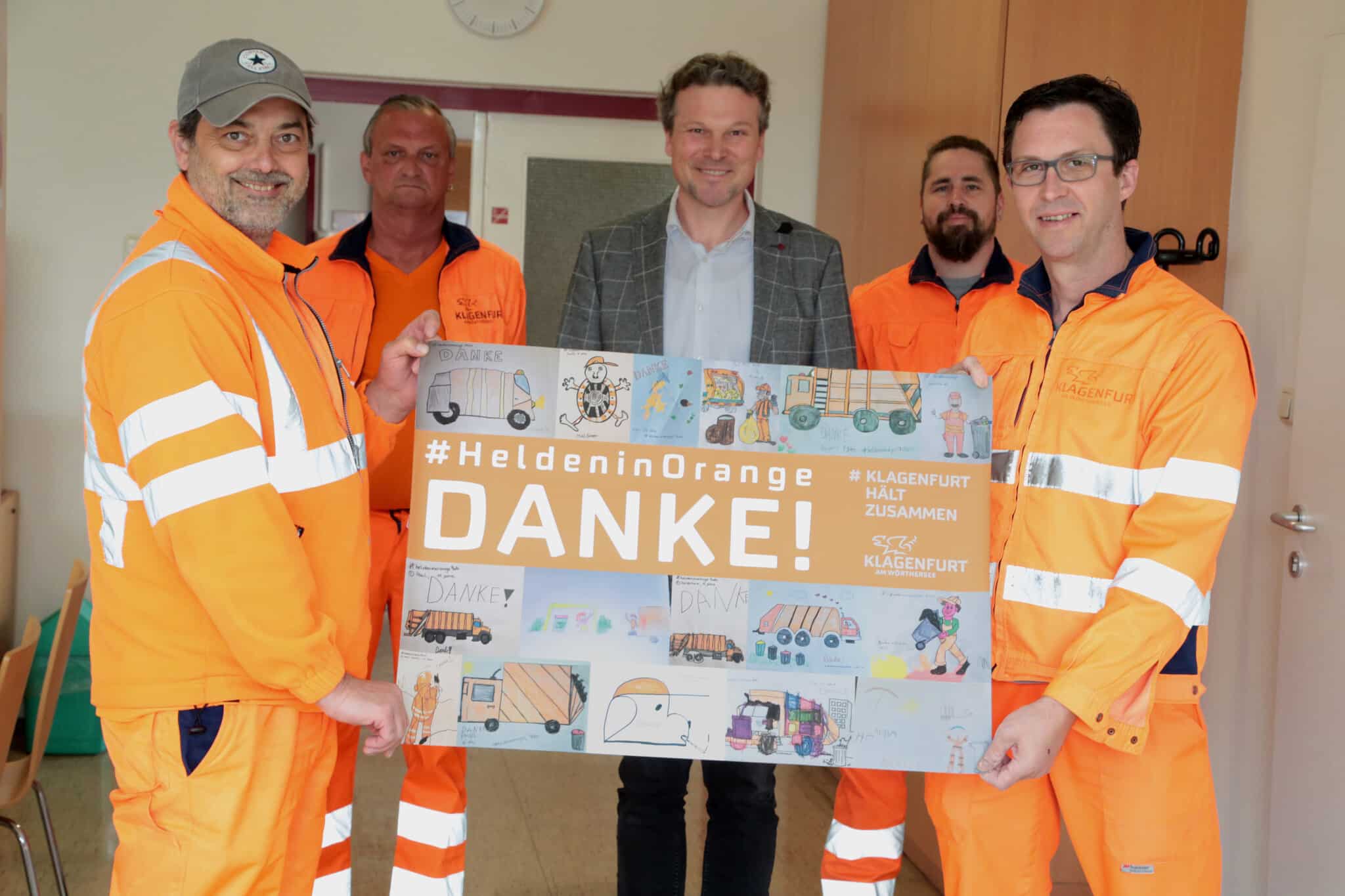 Entsorgungsreferent Vzbgm. Wolfgang Germ und Mitarbeiter der Entsorgung präsentieren die besten Kinderzeichnungen der Aktion „Helden in Orange“.