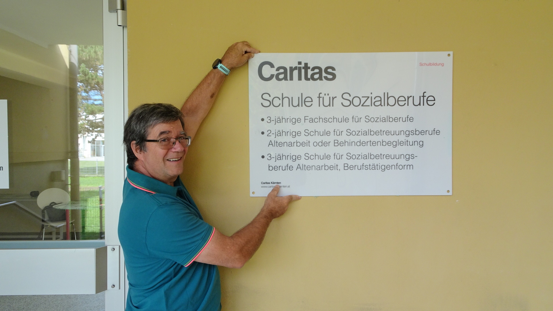 Direktor Roland Lassenberger beim Montieren des Schildes der Schule am neuen Standort in Wolfsberg. 
