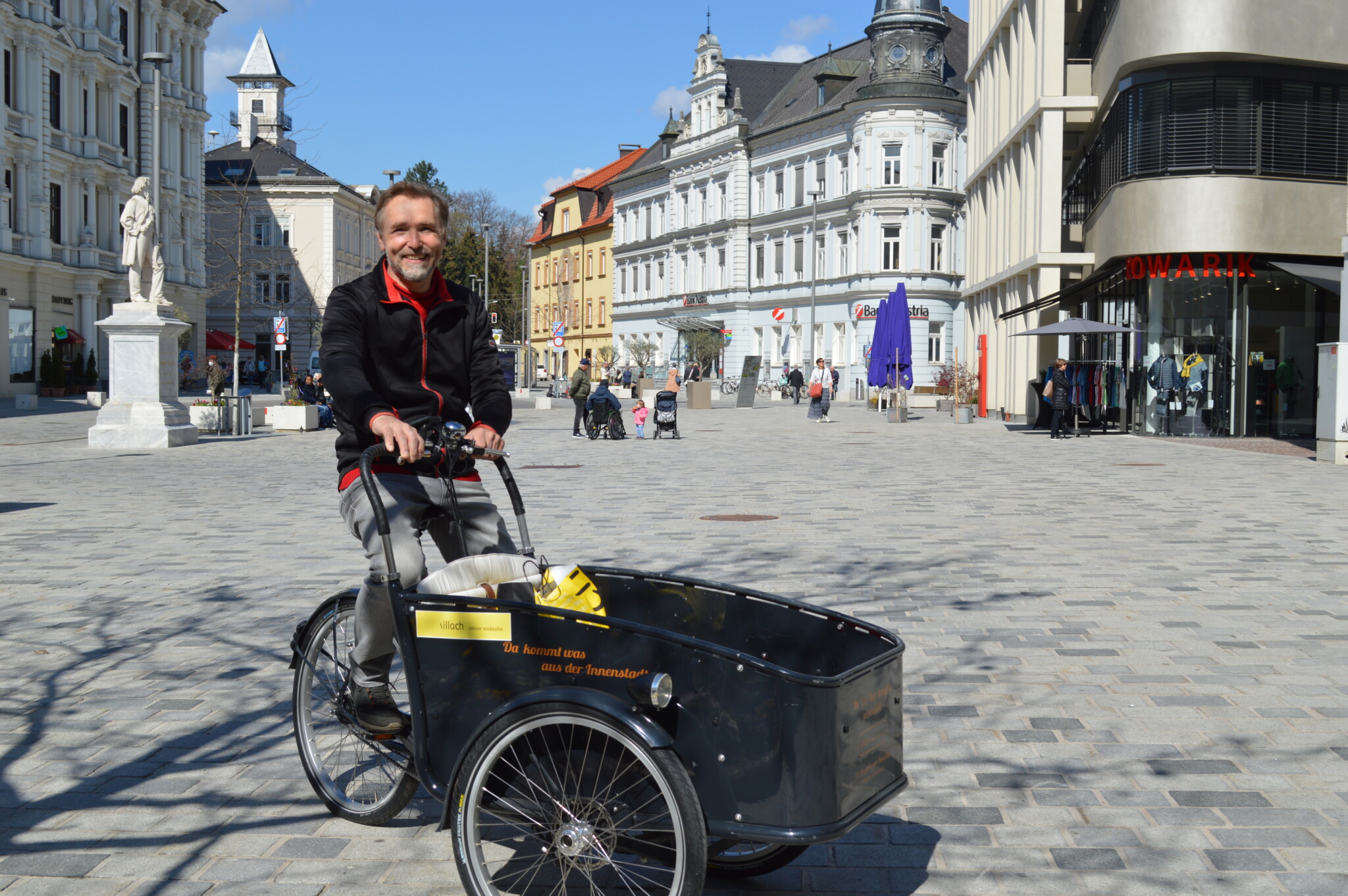 City-Bote Georg Moser ist mit seinem Elektro-Lastenfahrrad wieder in der Villacher Innenstadt unterwegs und bringt die schweren Einkaufstaschen der Innenstadtkunden zum Parkplatz oder auch nach Hause.